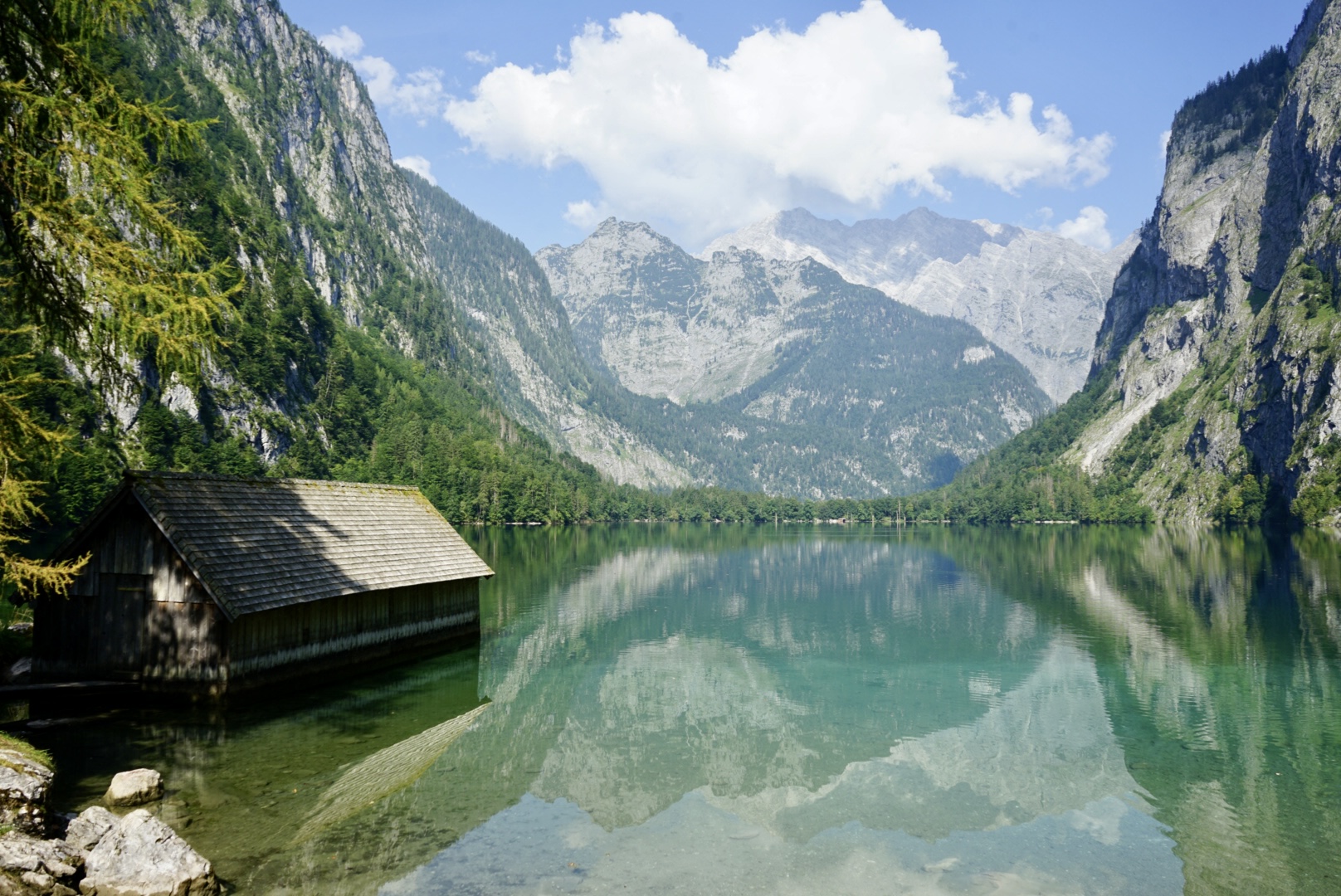 Blick auf den schönen Obersee in Berchtesgaden mit den Bergen im Hintergrund und einer Hütte im Vordergrund