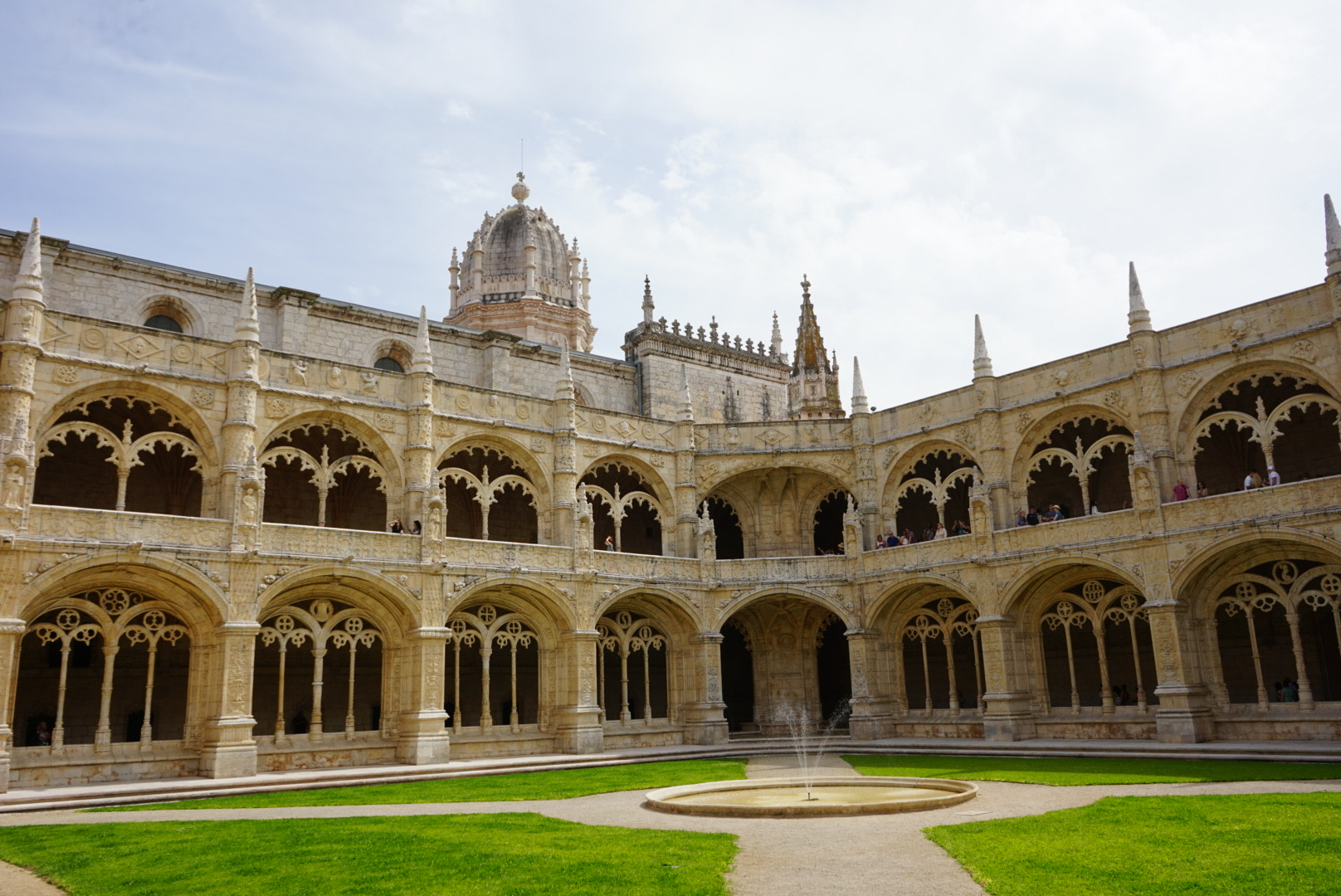 Der begrünte Innenhof des Mosteiro dos Jerónimos in Lissabon mit der Kuppel im Hintergrund